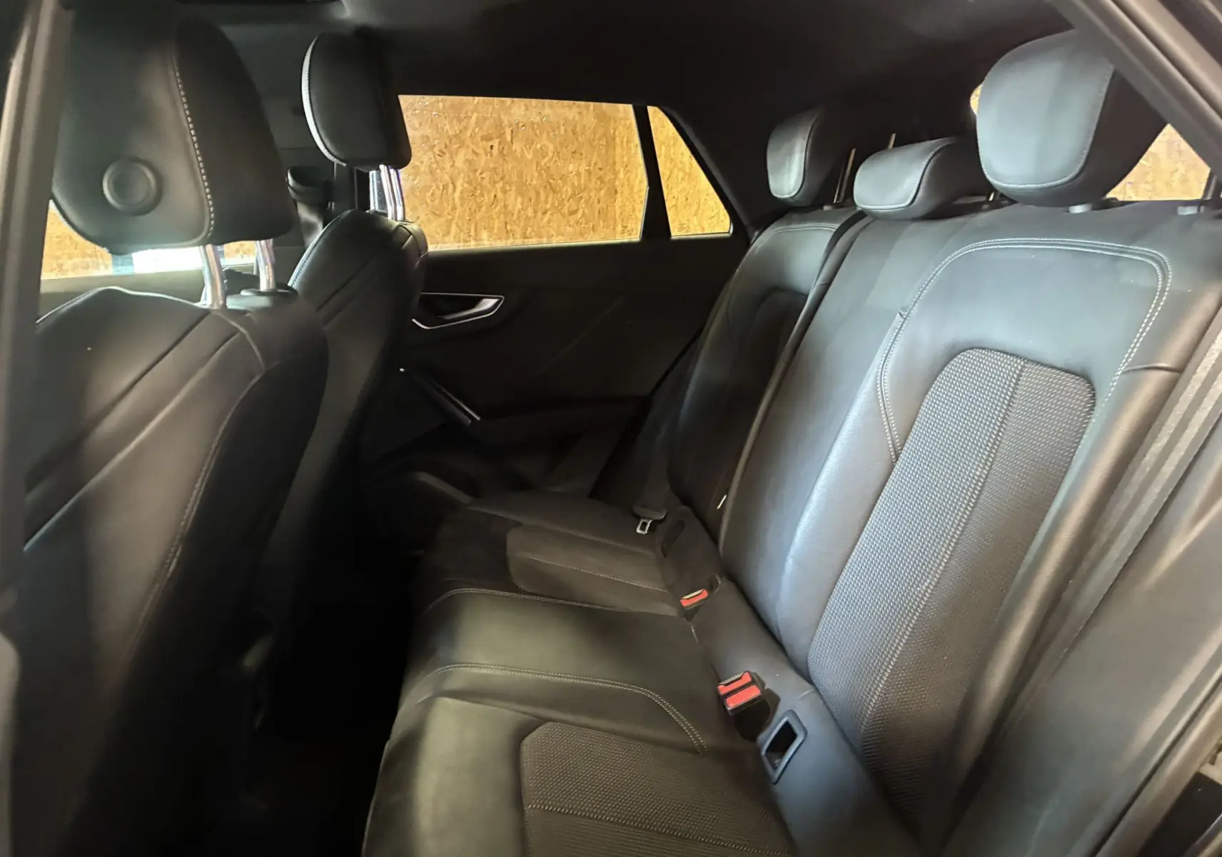 Vue intérieure côté droit des sièges arrière en cuir noir avec surpiqûres blanches de l'Audi Q2 2023.