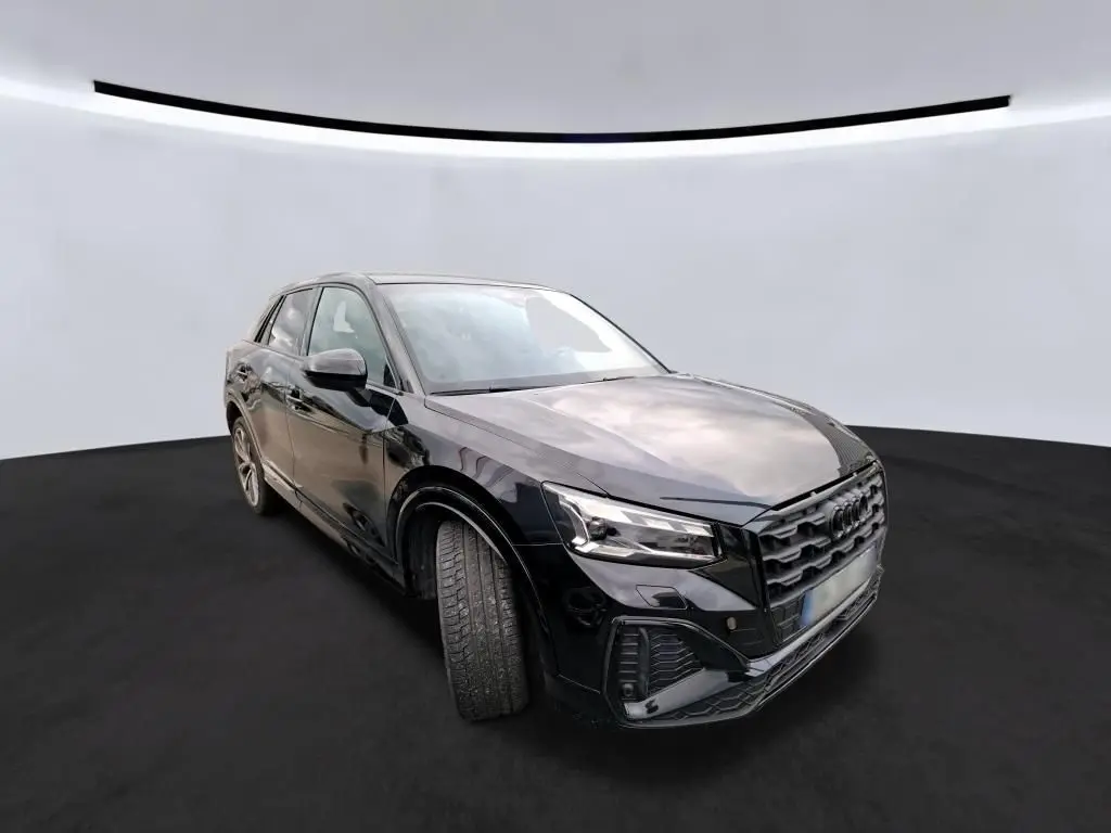 Audi Q2 noir vue de face dans un garage avec calandre noire et plaque Distinxion visible.