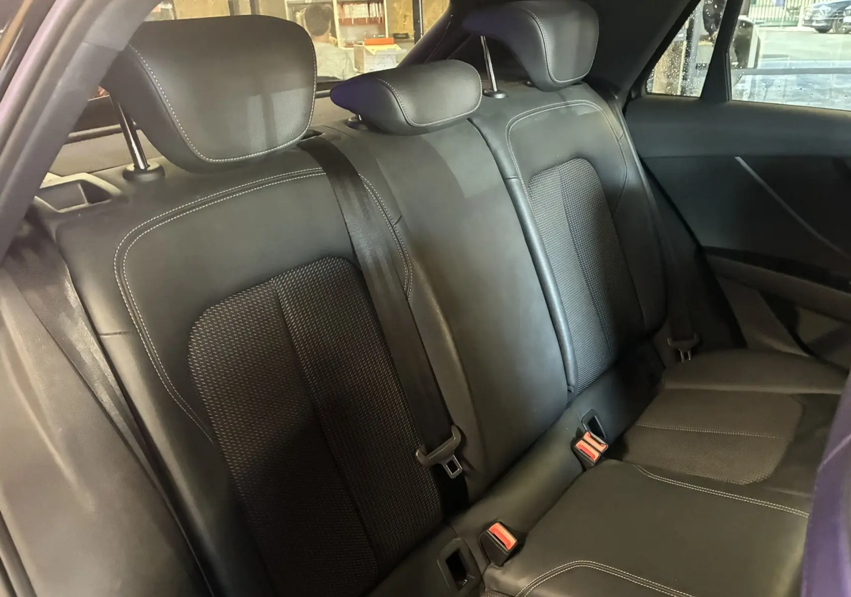 Vue intérieure de la banquette arrière en cuir noir de l'Audi Q2 2023 avec appuie-têtes et ceintures visibles.