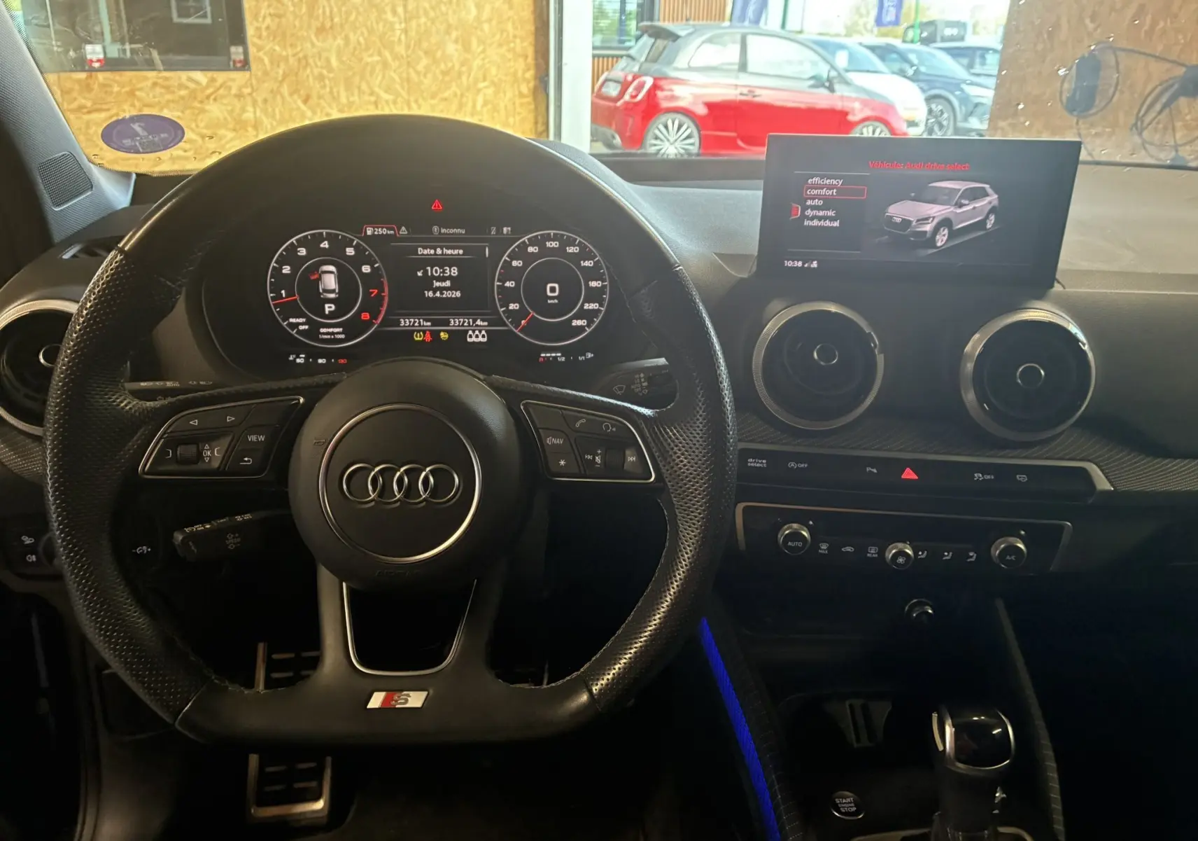 Vue intérieure centrée sur le volant sport Audi Q2 noir avec tableau de bord numérique et écran multimédia.