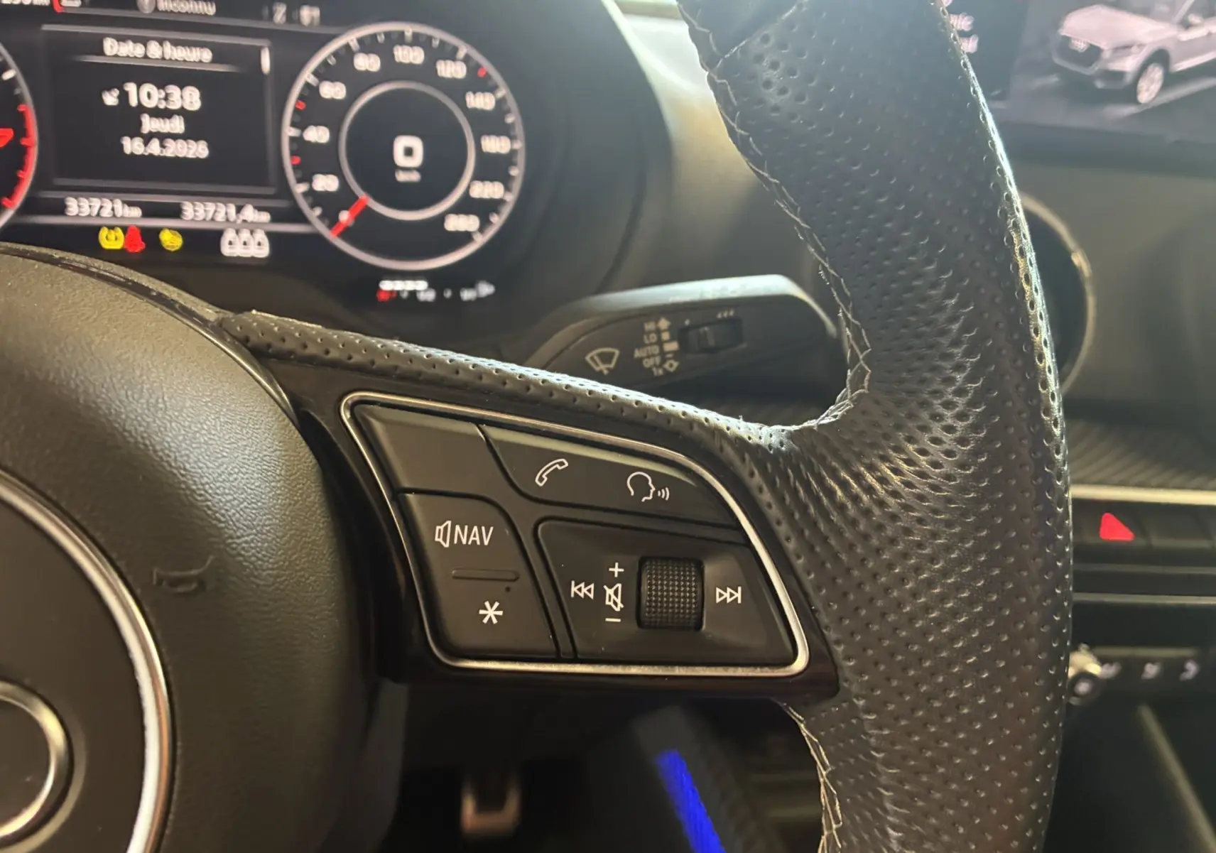 Gros plan sur le volant cuir perforé noir de l'Audi Q2 2023 avec commandes multifonctions et tableau de bord numérique.