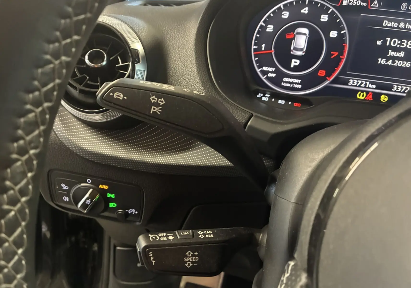 Vue rapprochée du tableau de bord noir d’un Audi Q2 2023, avec commandes au volant et affichage numérique du compteur.