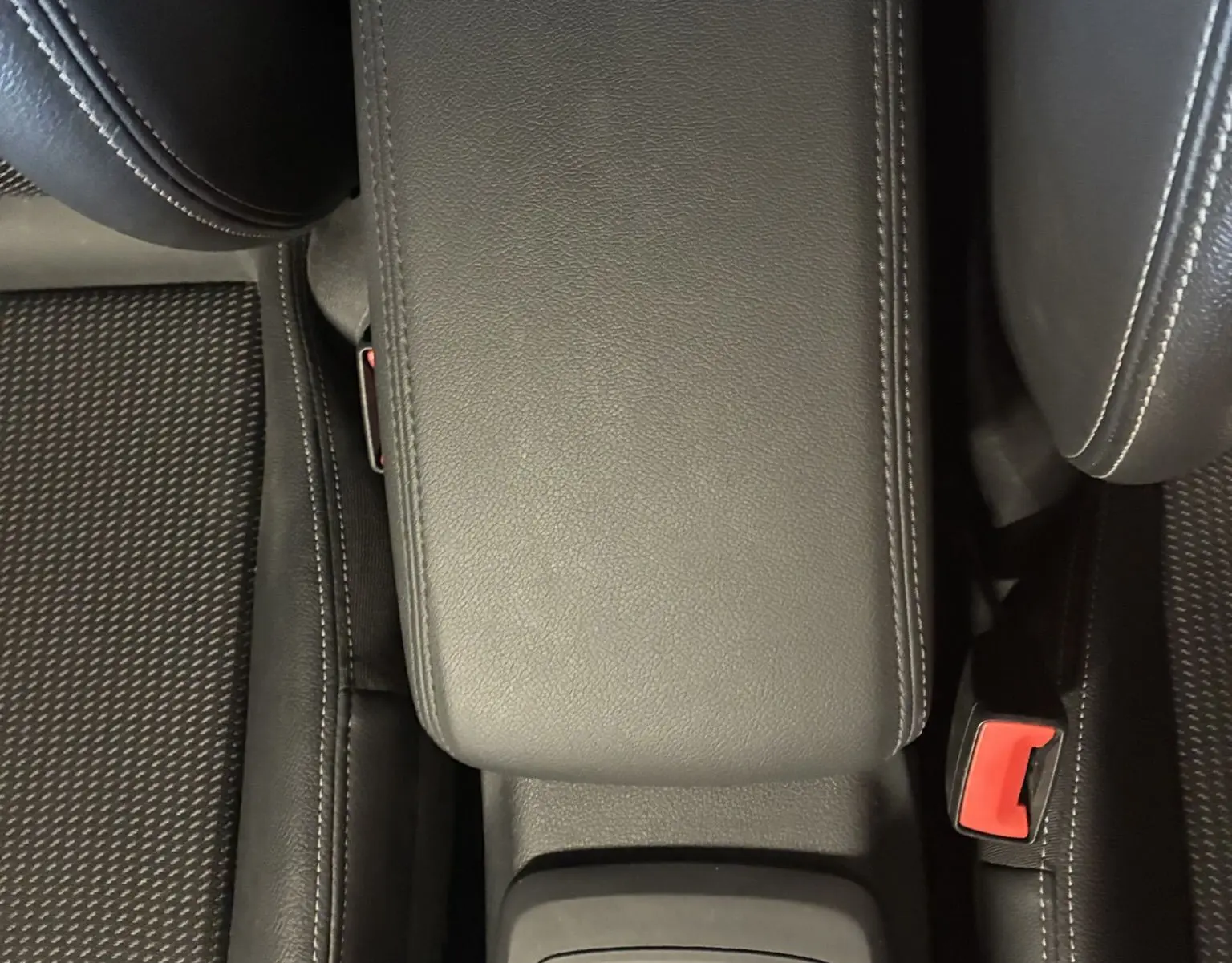 Vue plongeante sur l'accoudoir central noir et la console avec commandes du Audi Q2 2023 finition S-Line+