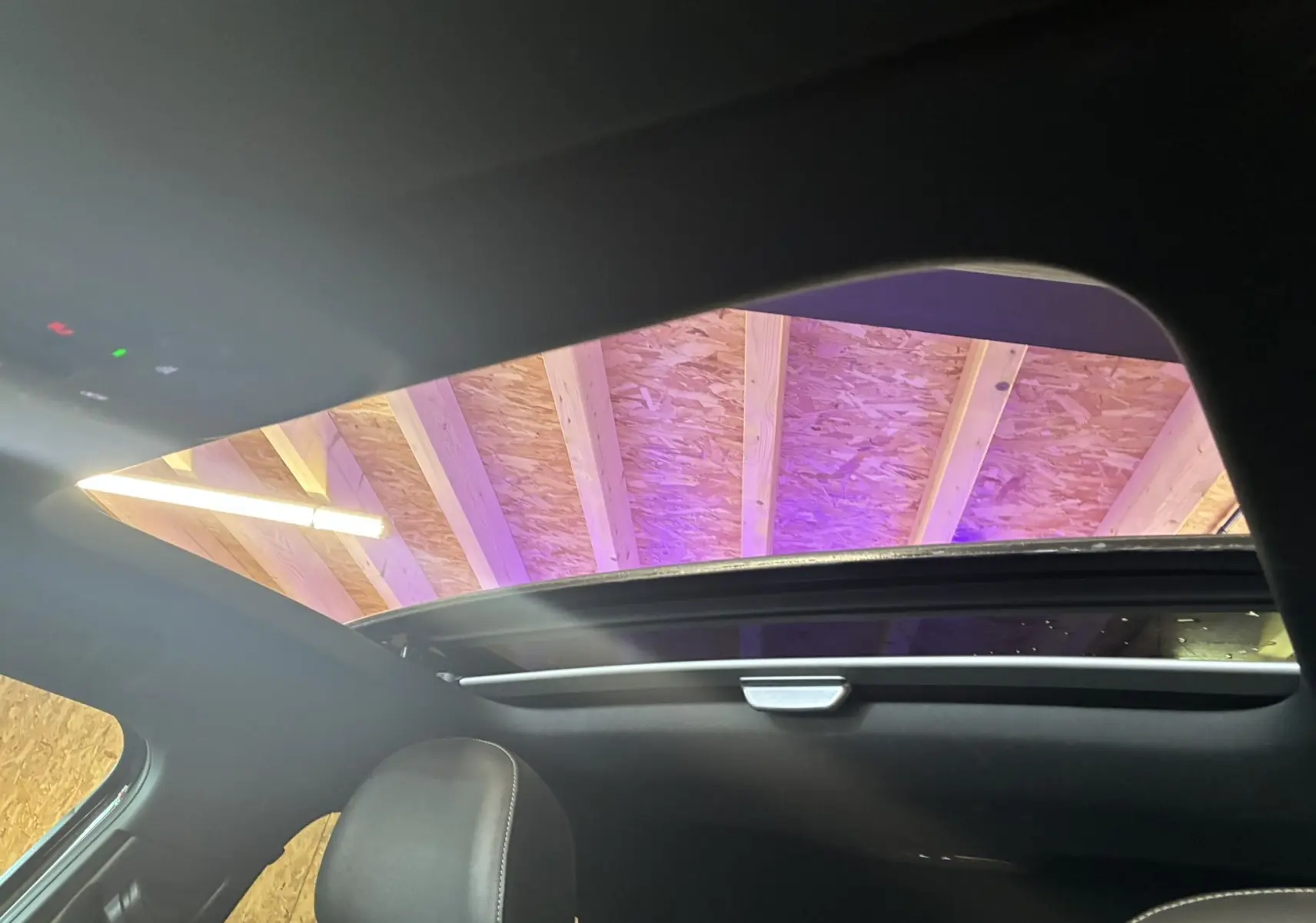 Vue intérieure du toit ouvrant panoramique ouvert de l'Audi Q2 noir, avec appuie-tête avant en cuir visible.