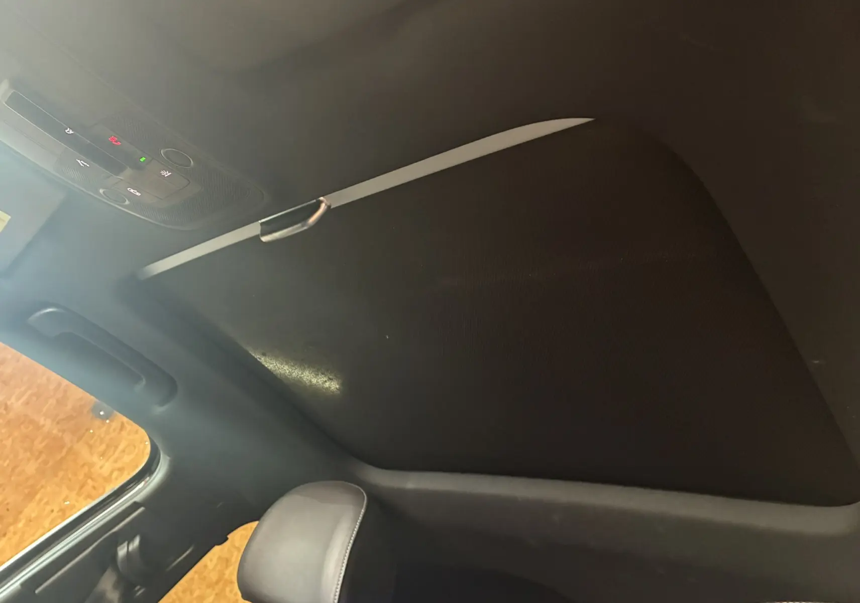 Toit ouvrant fermé et ciel de toit noir à l'intérieur de l'Audi Q2 2023, avec appuie-tête en cuir visible.