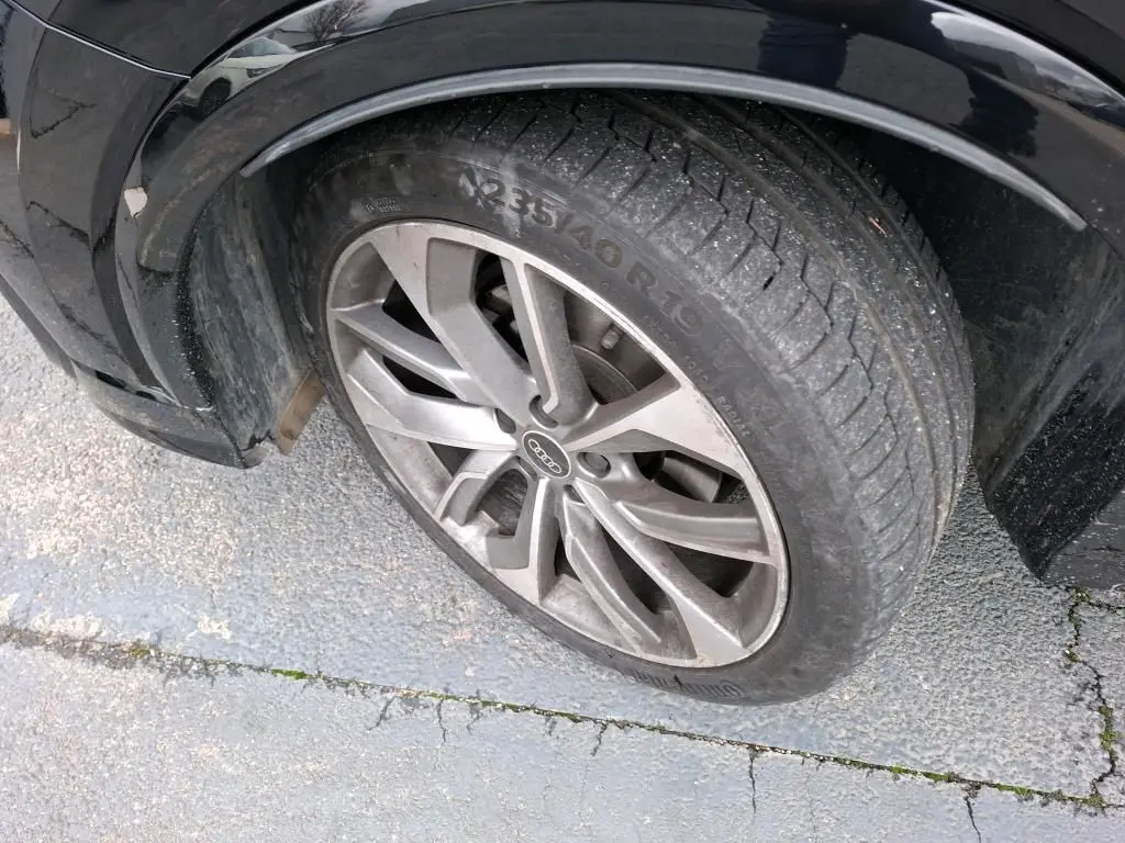 Audi Q2 noir vue 3/4 arrière droit en intérieur, jantes alliage et feux arrière LED visibles.