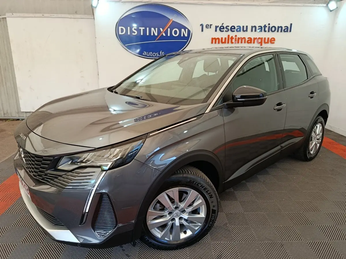 Peugeot 3008 gris foncé vue 3/4 avant droit, avec feux LED et calandre noire distinctive en showroom.