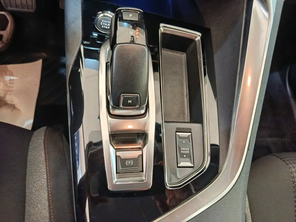 Gros plan sur la console centrale noire brillante du Peugeot 3008 gris foncé, avec levier de vitesse et commande Drive Mode.