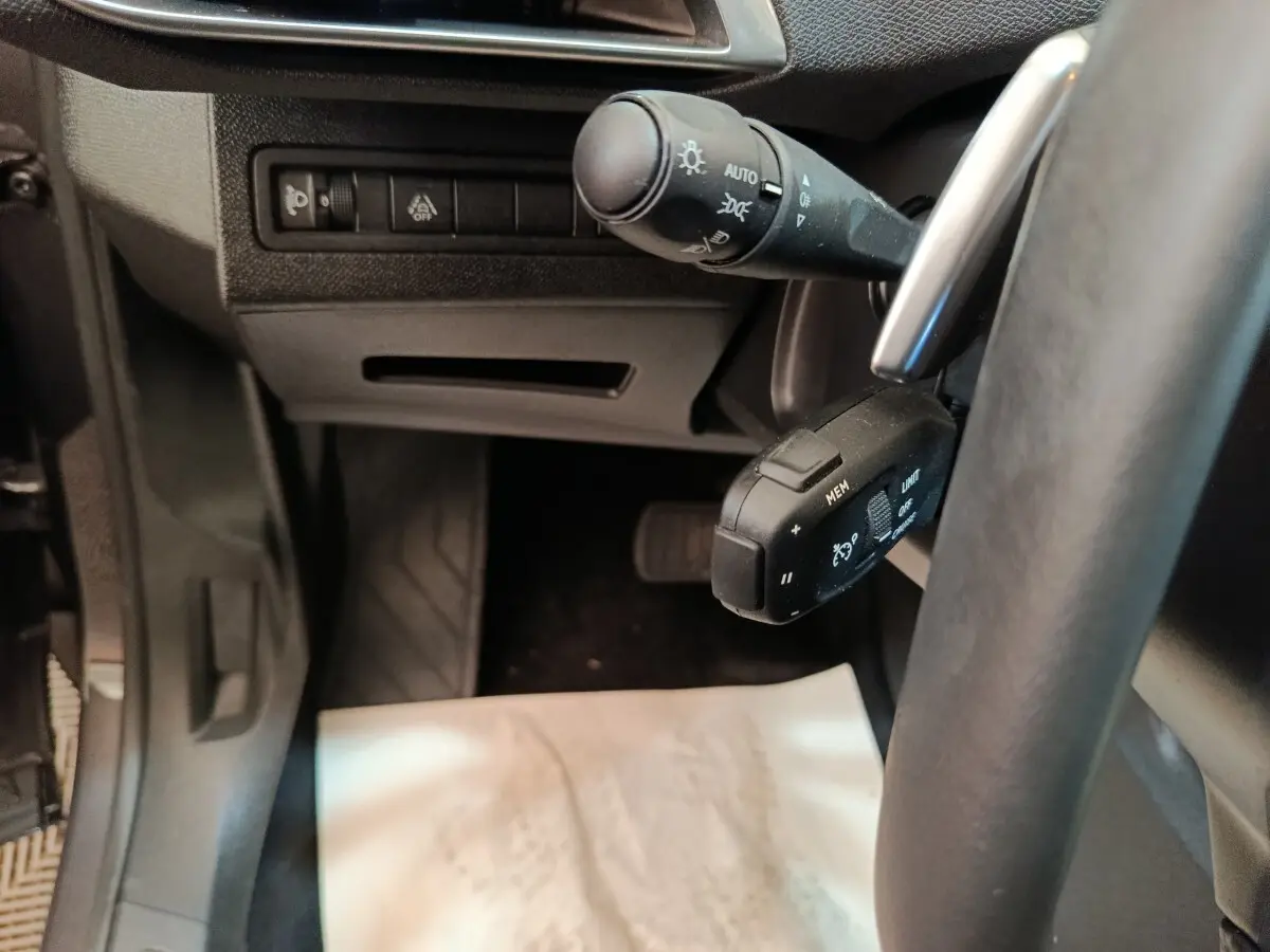 Vue rapprochée côté gauche du volant du Peugeot 3008 gris foncé, montrant les commandes de phares et régulateur de vitesse.