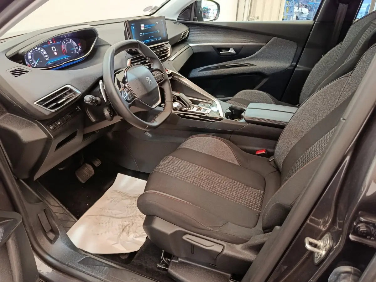 Intérieur côté conducteur du Peugeot 3008 gris foncé 2022, avec tableau de bord digital et volant cuir multifonctions.