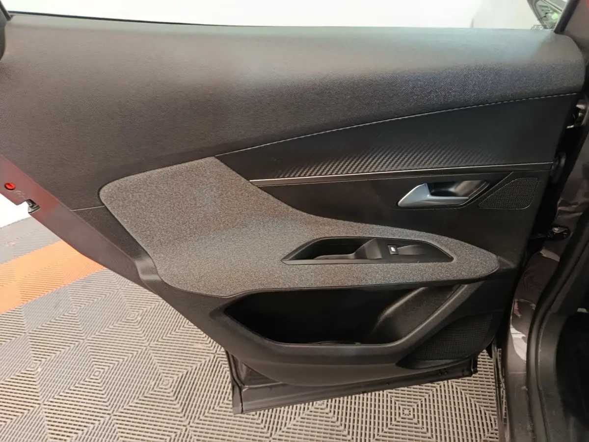 Porte intérieure côté droit de Peugeot 3008 gris foncé, avec habillage tissu et plastique noir, poignée argentée.