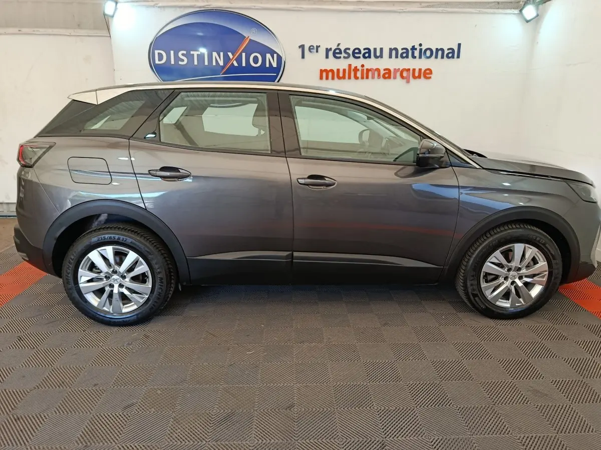 Profil latéral droit d'un Peugeot 3008 gris foncé 2022 garé en intérieur sur sol damier, avec logo Distinxion en arrière-plan.