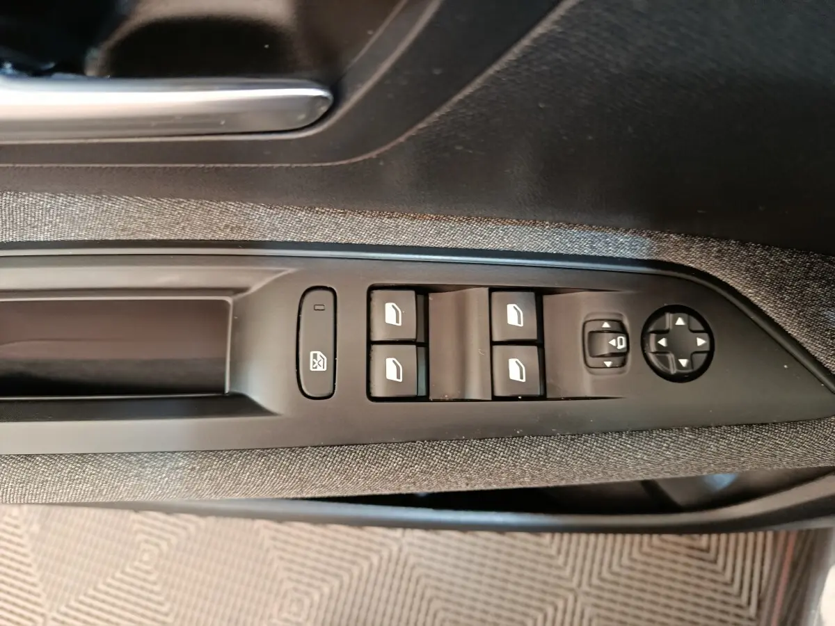 Vue rapprochée des commandes de lève-vitres et réglage des rétroviseurs côté conducteur du Peugeot 3008 gris foncé 2022.