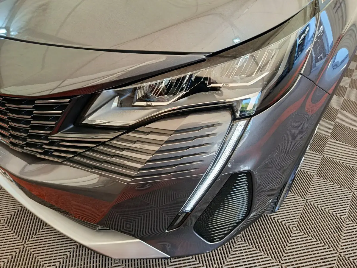 Gros plan sur le phare avant droit du Peugeot 3008 gris foncé, mettant en valeur la calandre et les feux LED distinctifs.
