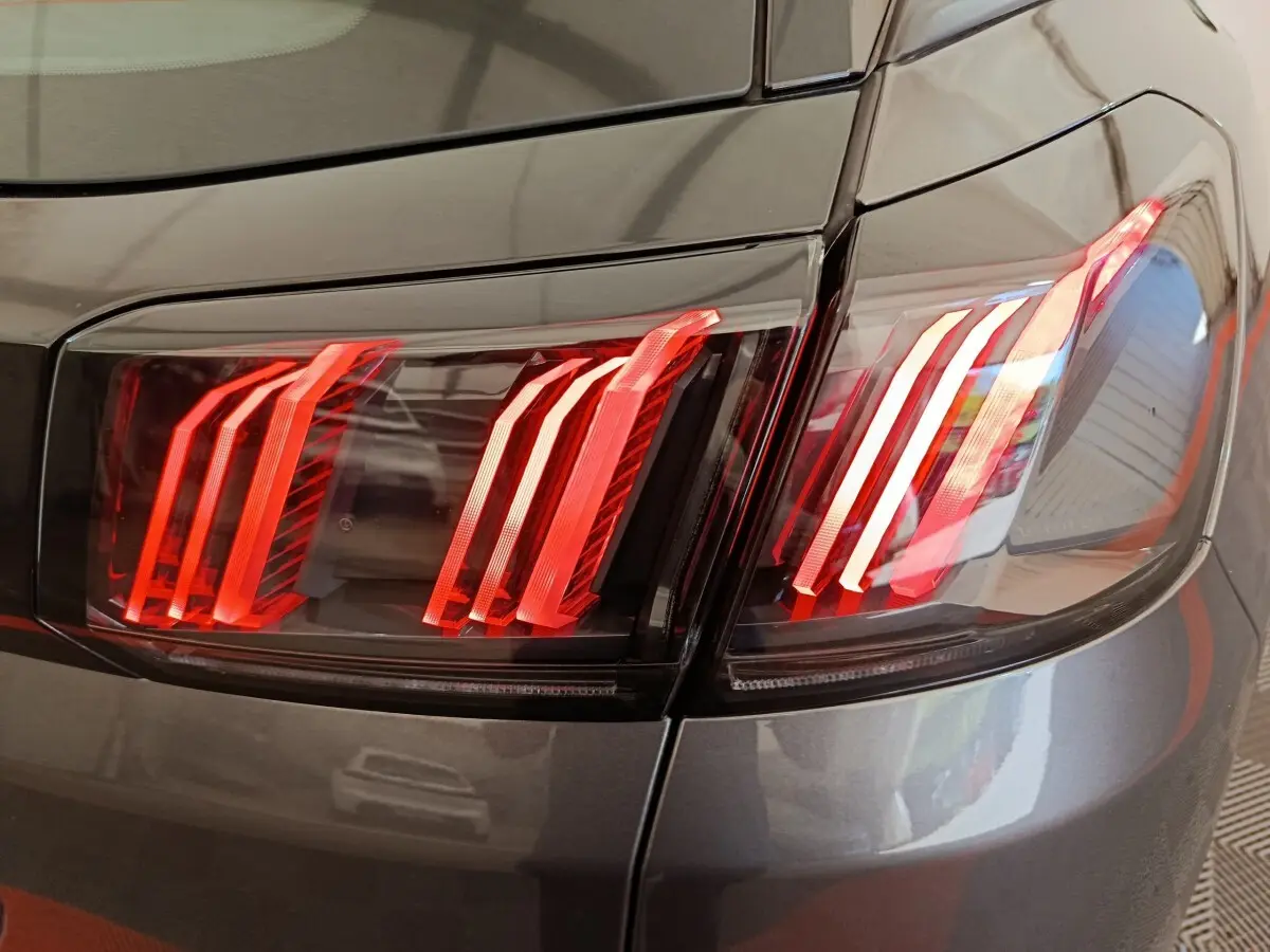 Gros plan sur les feux arrière droits rouges d’un Peugeot 3008 gris foncé, soulignant le design moderne du véhicule.