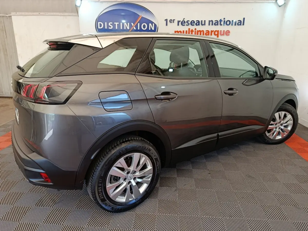 Peugeot 3008 gris foncé vue 3/4 arrière droit, avec feux arrière LED et jantes alliage visibles en intérieur showroom.