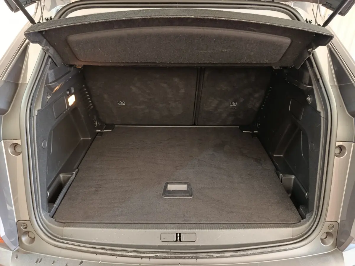 Coffre ouvert d’un Peugeot 3008 gris foncé, vue arrière montrant l’espace de chargement vide et la tablette de séparation.