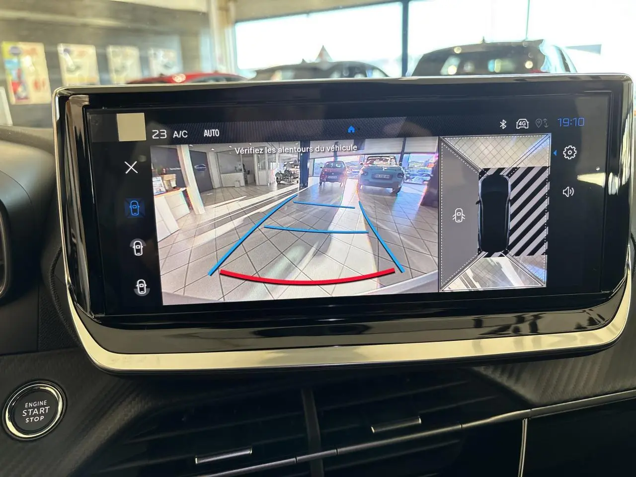 Écran tactile intérieur montrant la caméra de recul et l'aide au stationnement du Peugeot 2008 bleu, vue de face.