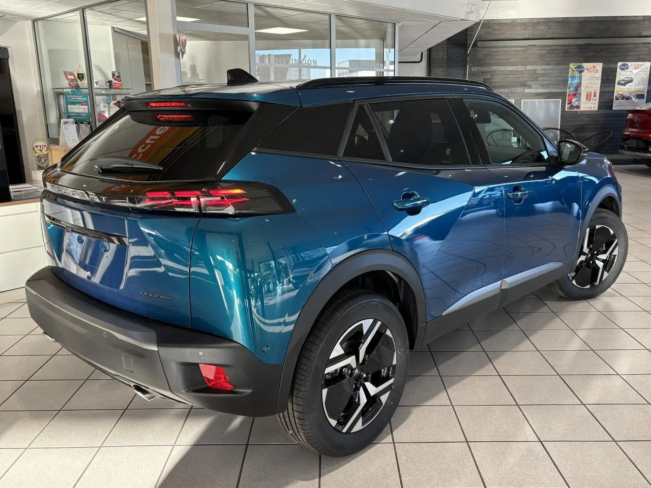 Peugeot 2008 bleu en 3/4 arrière droit, avec toit noir, feux LED à 3 griffes et jantes alliage bi-ton 17 pouces.