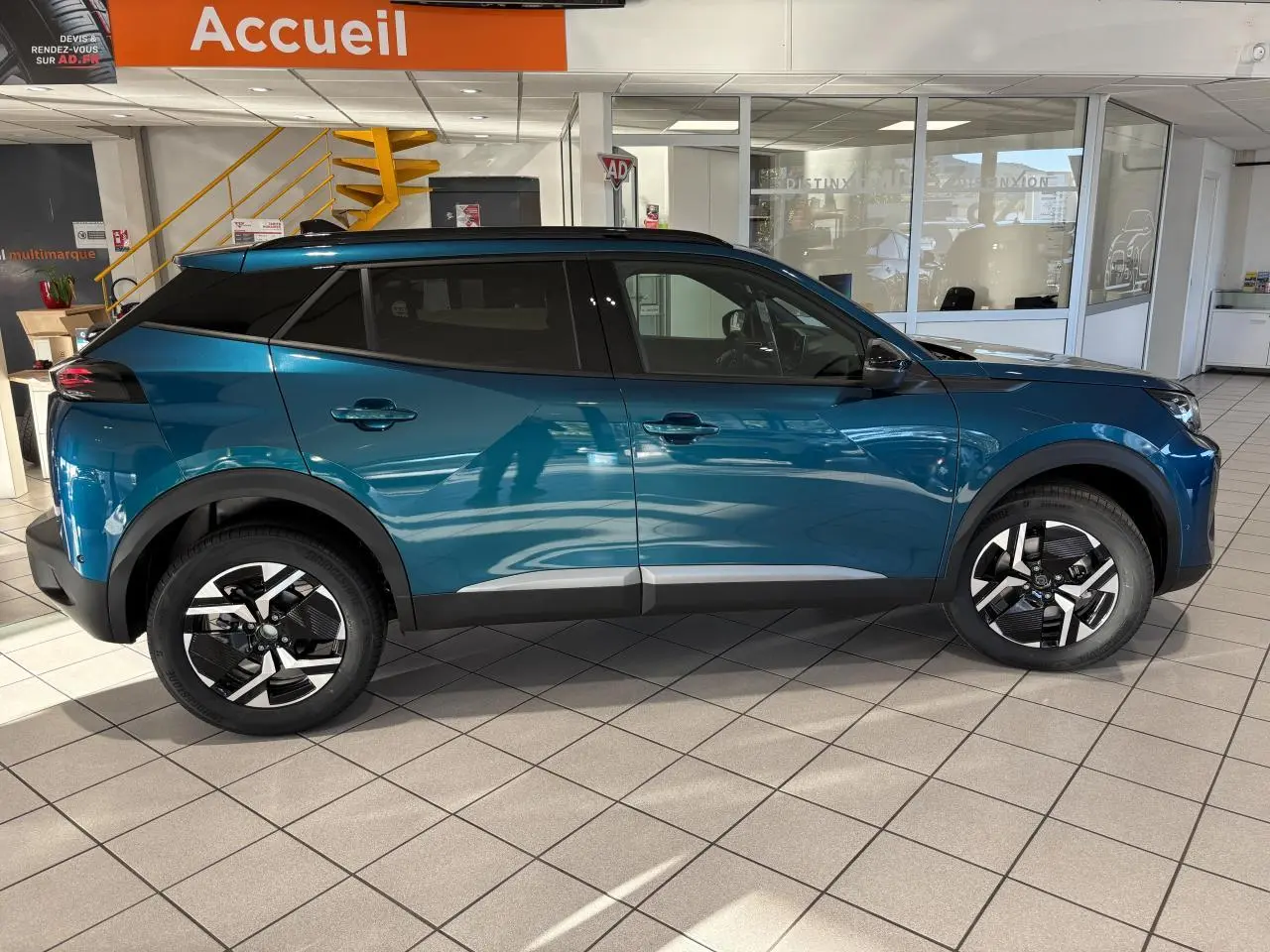Vue latérale droite du Peugeot 2008 hybride bleu avec jantes alliage bi-ton et protections noires sur les passages de roue.