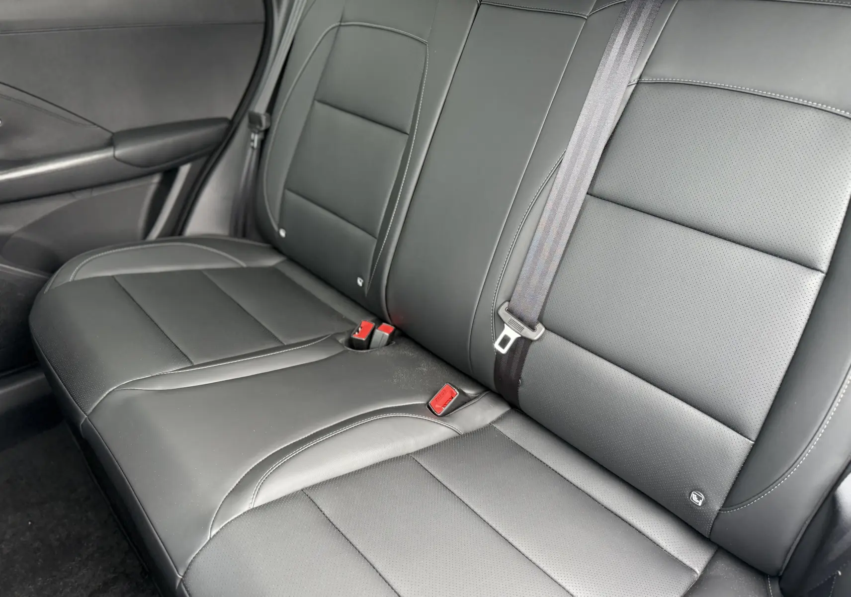 Vue intérieure du siège arrière en cuir noir du MG MOTOR ZS 1.5 HYBRID+ 197 LUXURY, avec ceinture de sécurité visible.