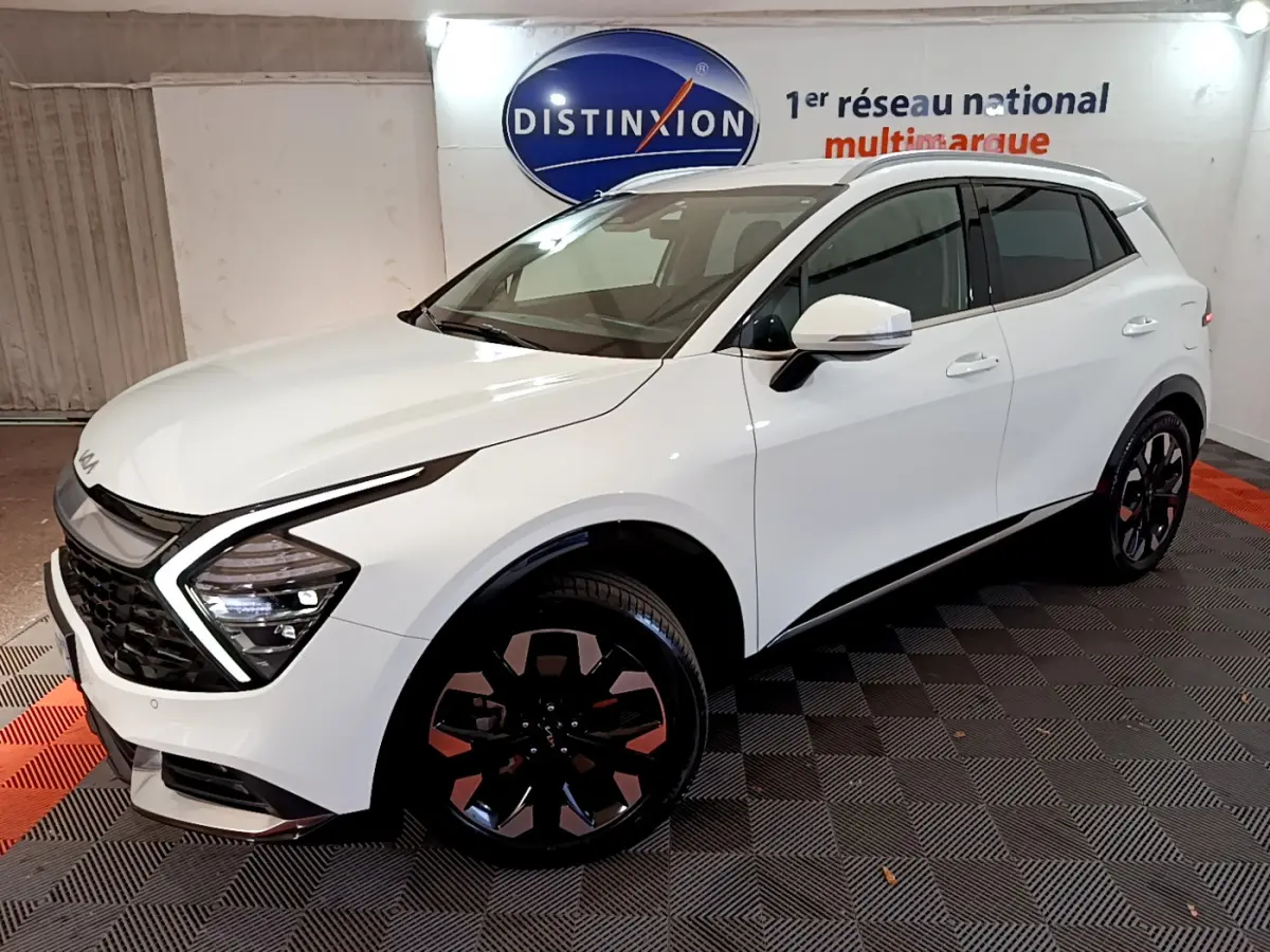 KIA SPORTAGE blanc en vue 3/4 avant droit, avec phares LED en forme de flèche et jantes noires distinctives.