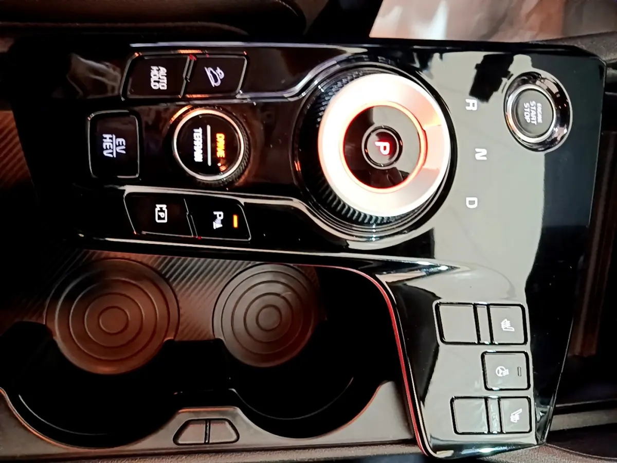 Gros plan sur la console centrale noire brillante du Kia Sportage 2022 avec sélecteur rotatif et boutons de commande.
