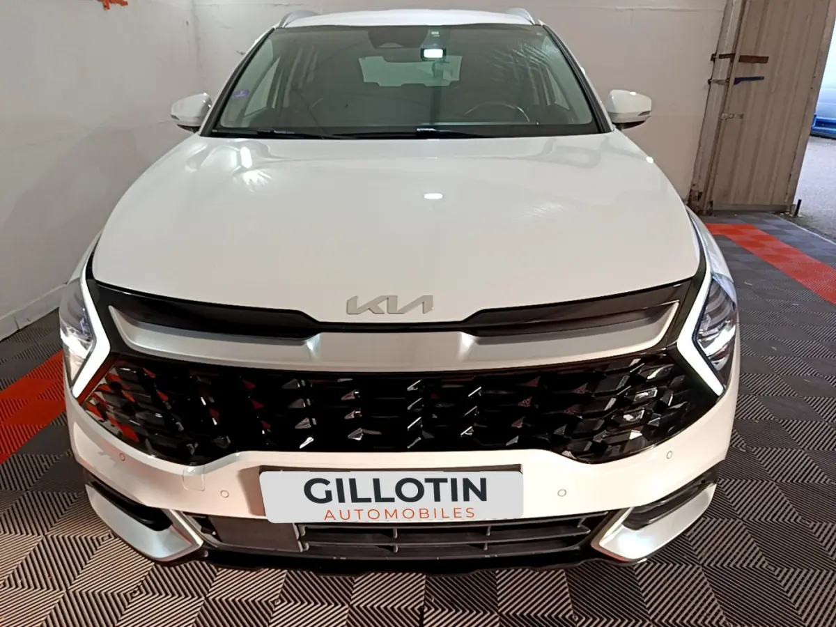 Vue avant rapprochée d'un KIA Sportage blanc 2022 avec calandre noire brillante et phares LED en V.