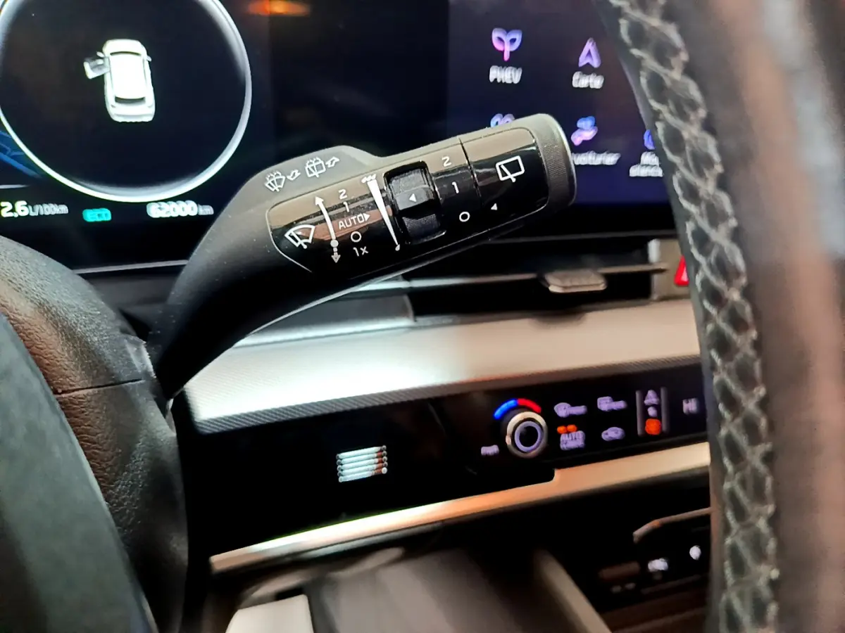 Gros plan sur la commande d’essuie-glace à gauche du volant dans l’habitacle du KIA SPORTAGE blanc 2022 hybride rechargeable.