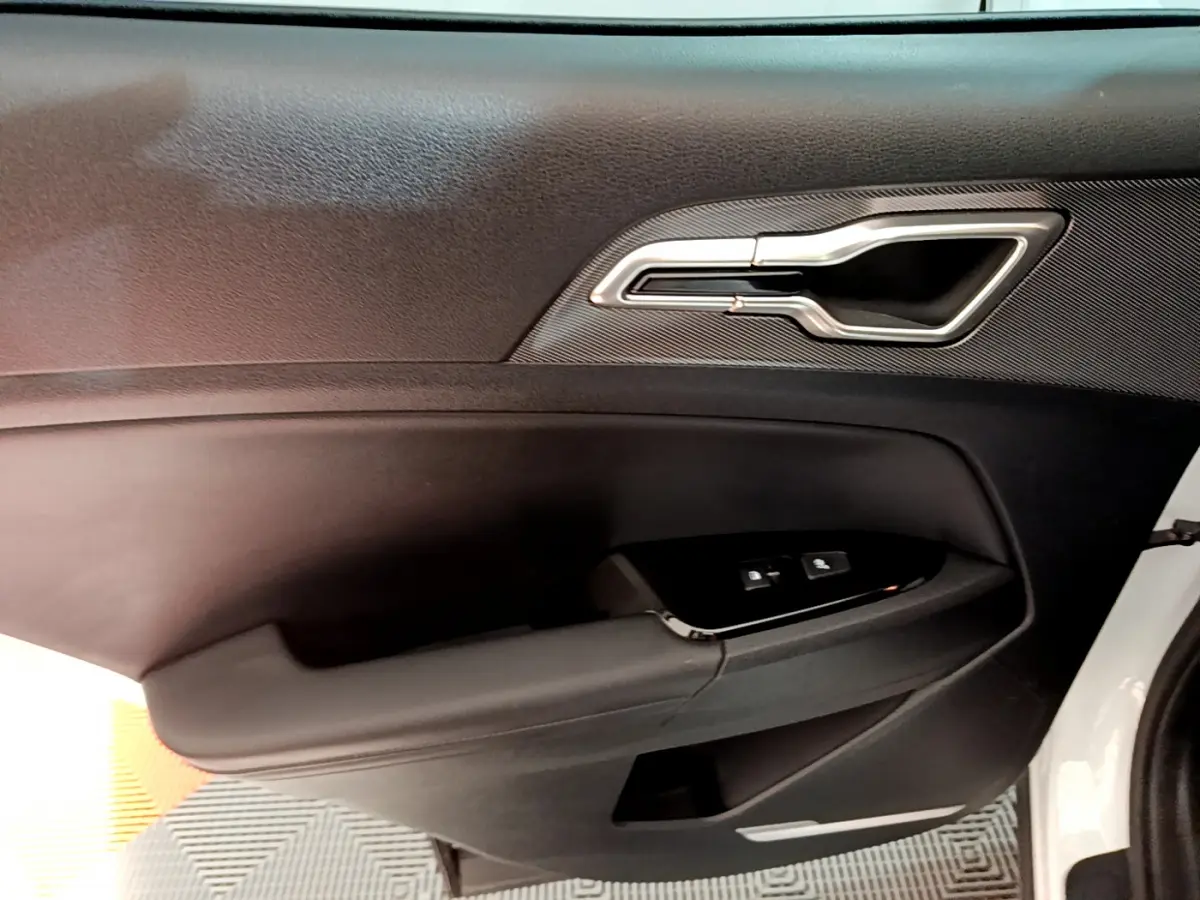 Poignée intérieure côté conducteur noire avec insert argenté sur la portière d'un KIA SPORTAGE blanc 2022 hybride rechargeable.