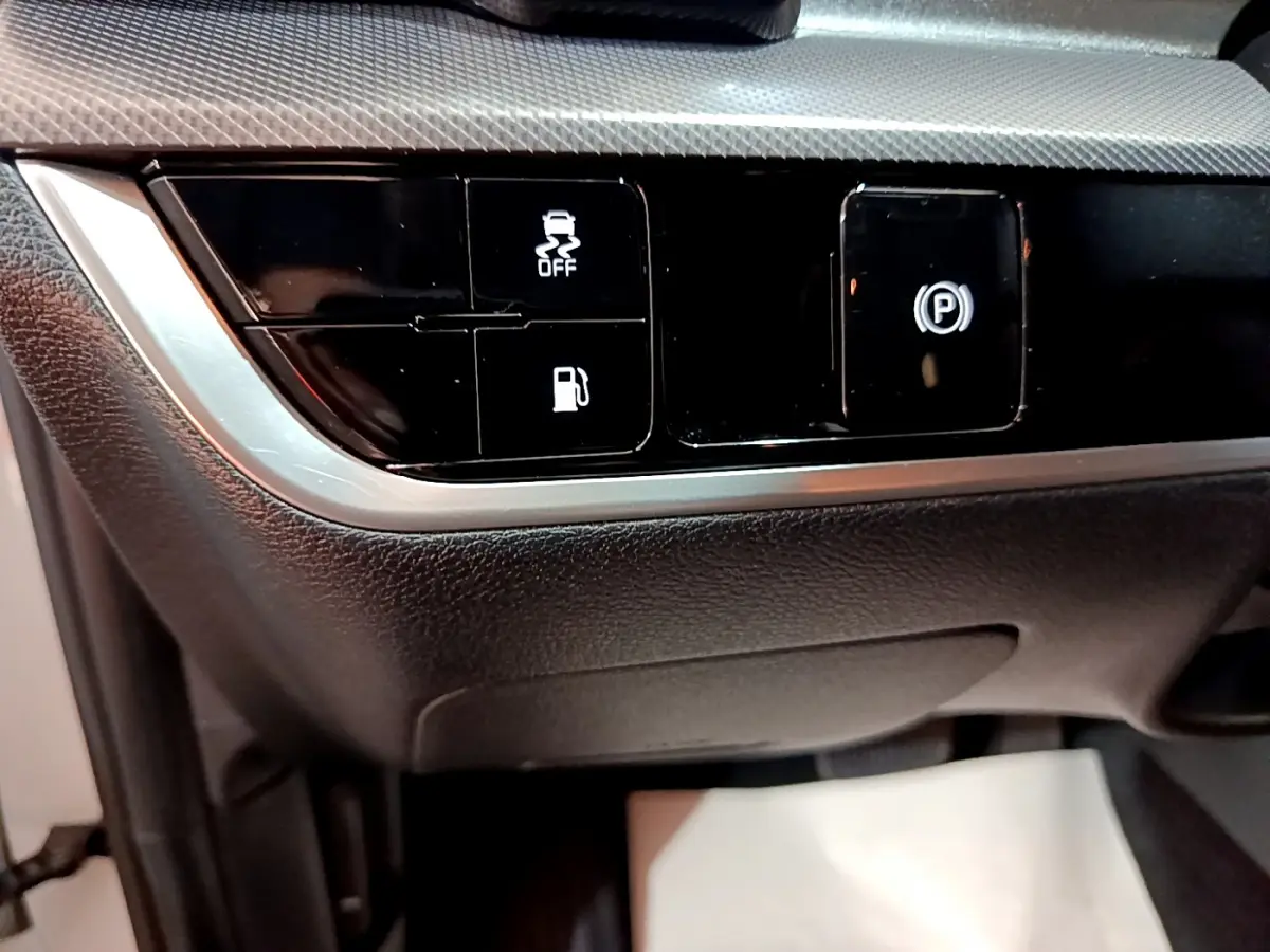 Gros plan sur les commandes noires du tableau de bord du Kia Sportage blanc 2022, avec boutons d'assistance et frein à main électrique.