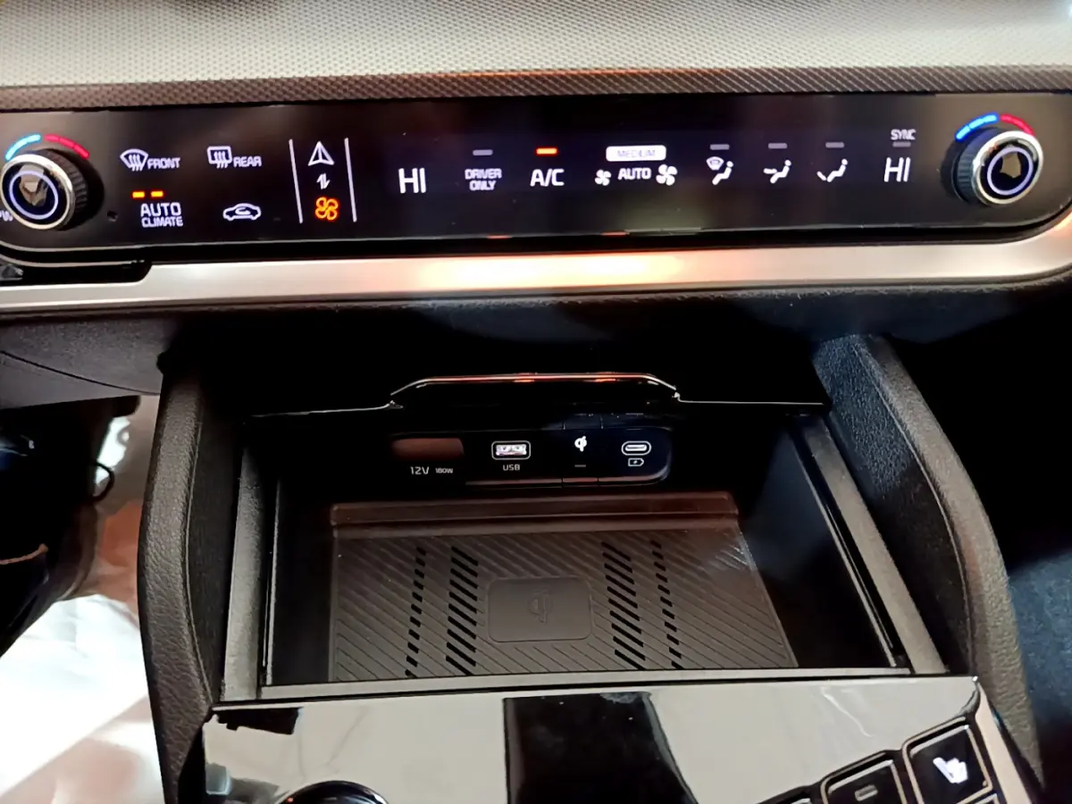 Détail de la console centrale du Kia Sportage blanc 2022 avec commandes climatisation et zone de recharge sans fil.