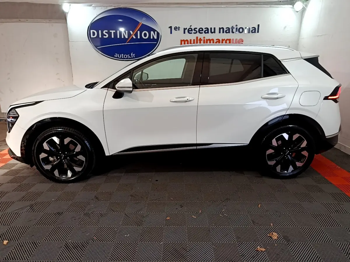 Profil côté gauche du KIA SPORTAGE blanc hybride rechargeable 2022 avec jantes noires et feux arrière LED distinctifs.