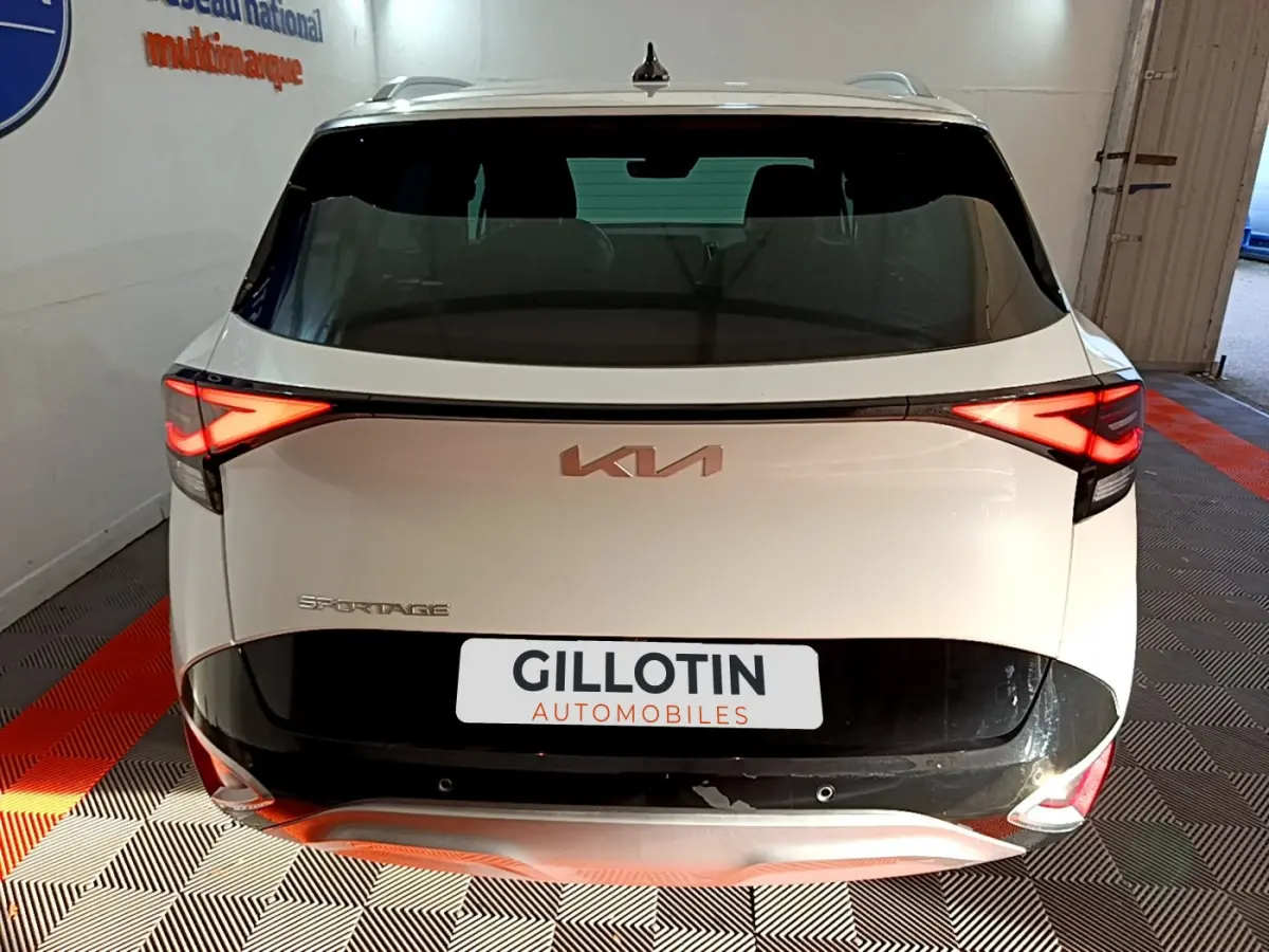 Vue arrière d'un KIA Sportage blanc 2022 avec feux LED allumés et logo KIA visible sur le hayon.