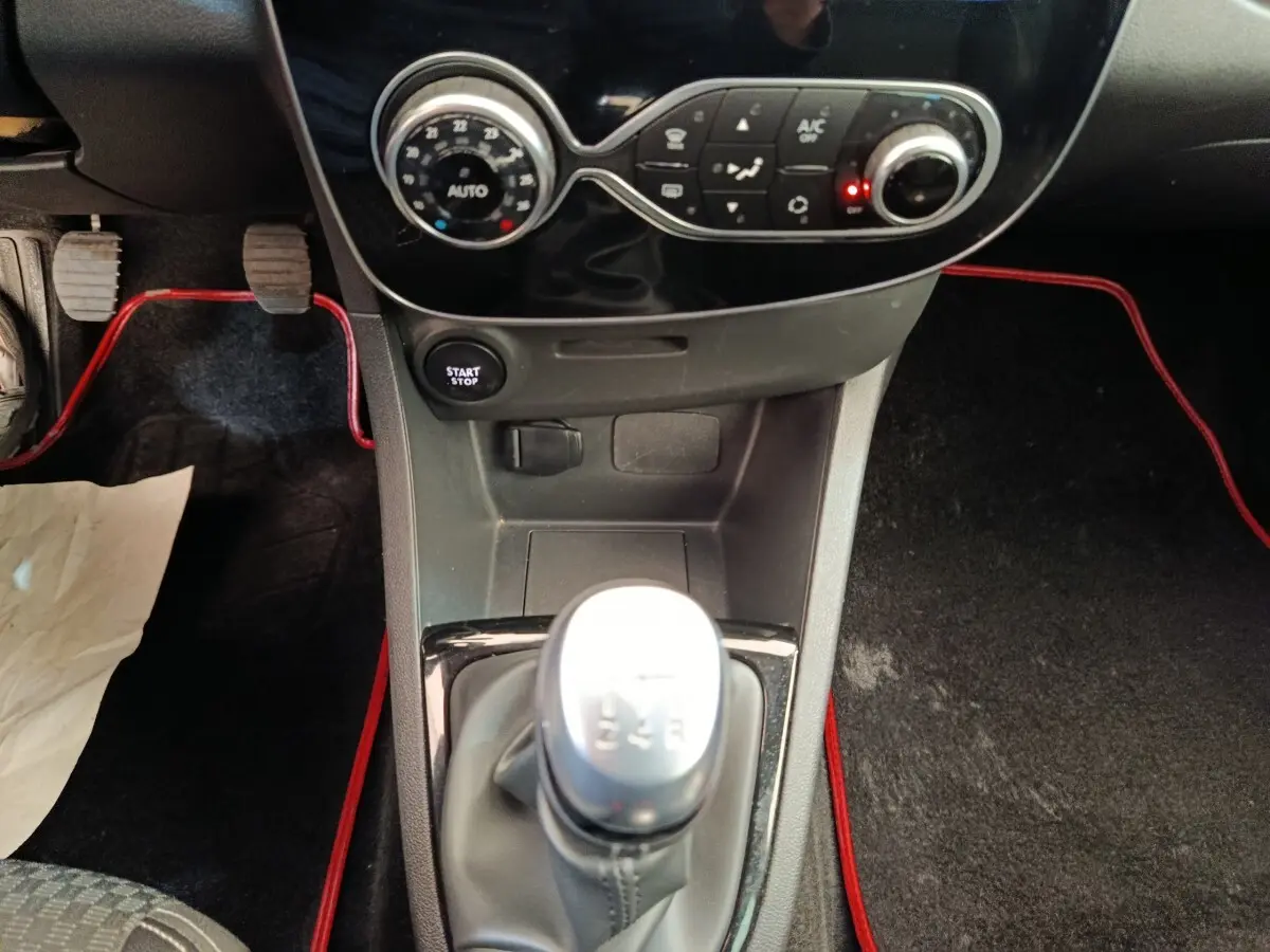 Vue rapprochée de la console centrale de la Renault Clio Intens rouge 2018 avec levier de vitesse manuel et bouton start/stop.