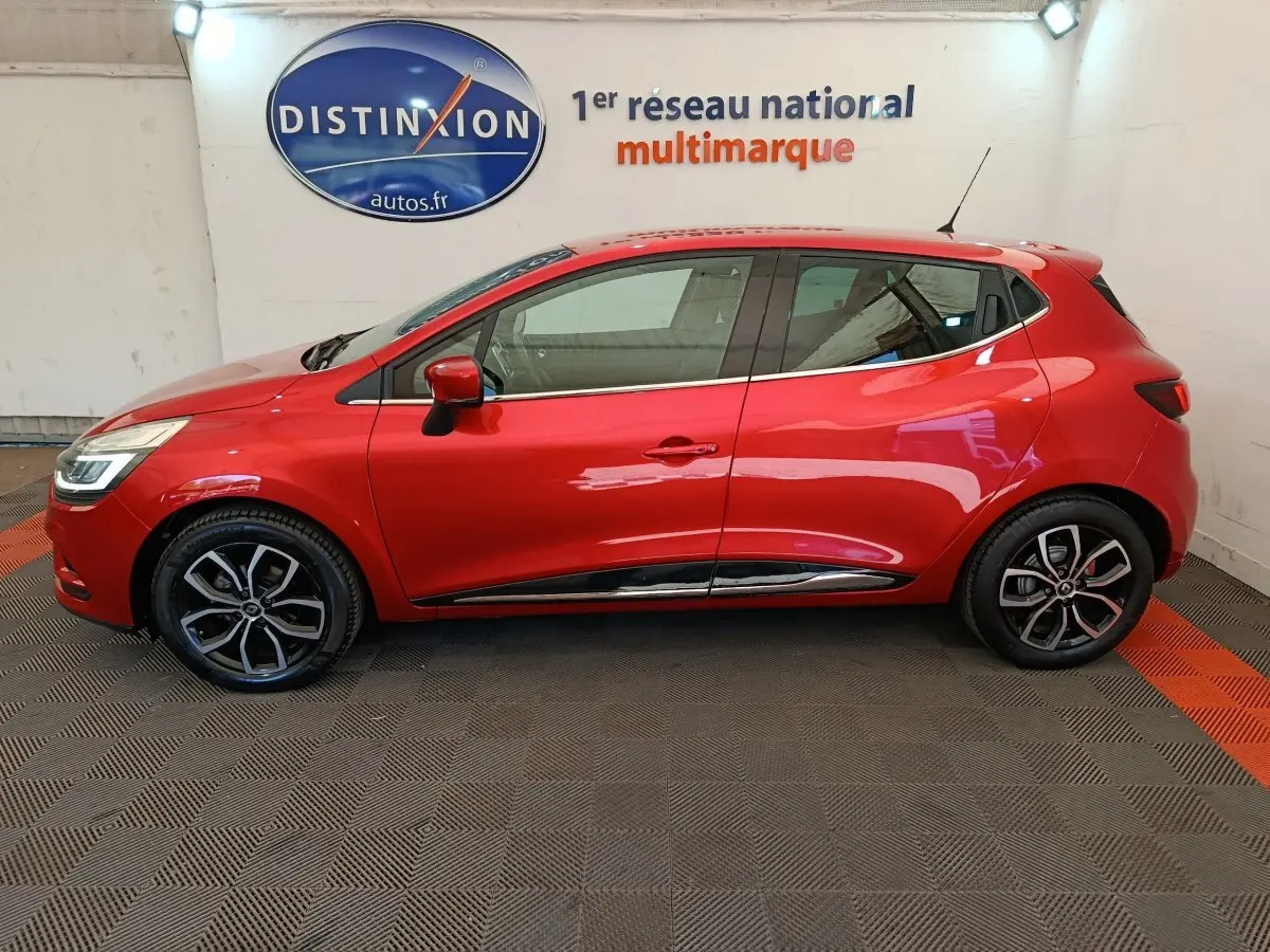 Profil côté gauche d'une Renault Clio Intens Energy TCe 90 rouge de 2018, avec jantes alliage et rétroviseurs assortis.