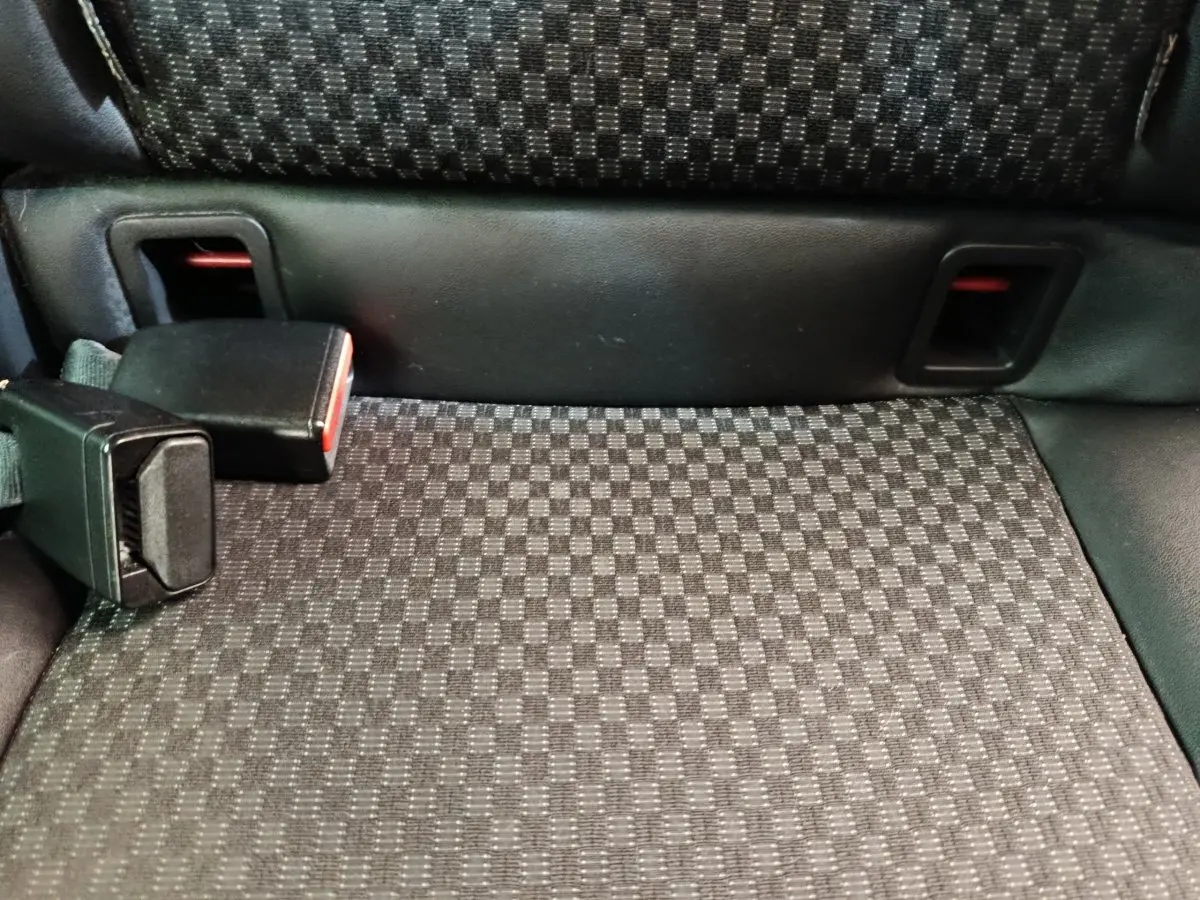 Gros plan sur la banquette arrière noire à motifs carrés avec boucle de ceinture de sécurité visible.