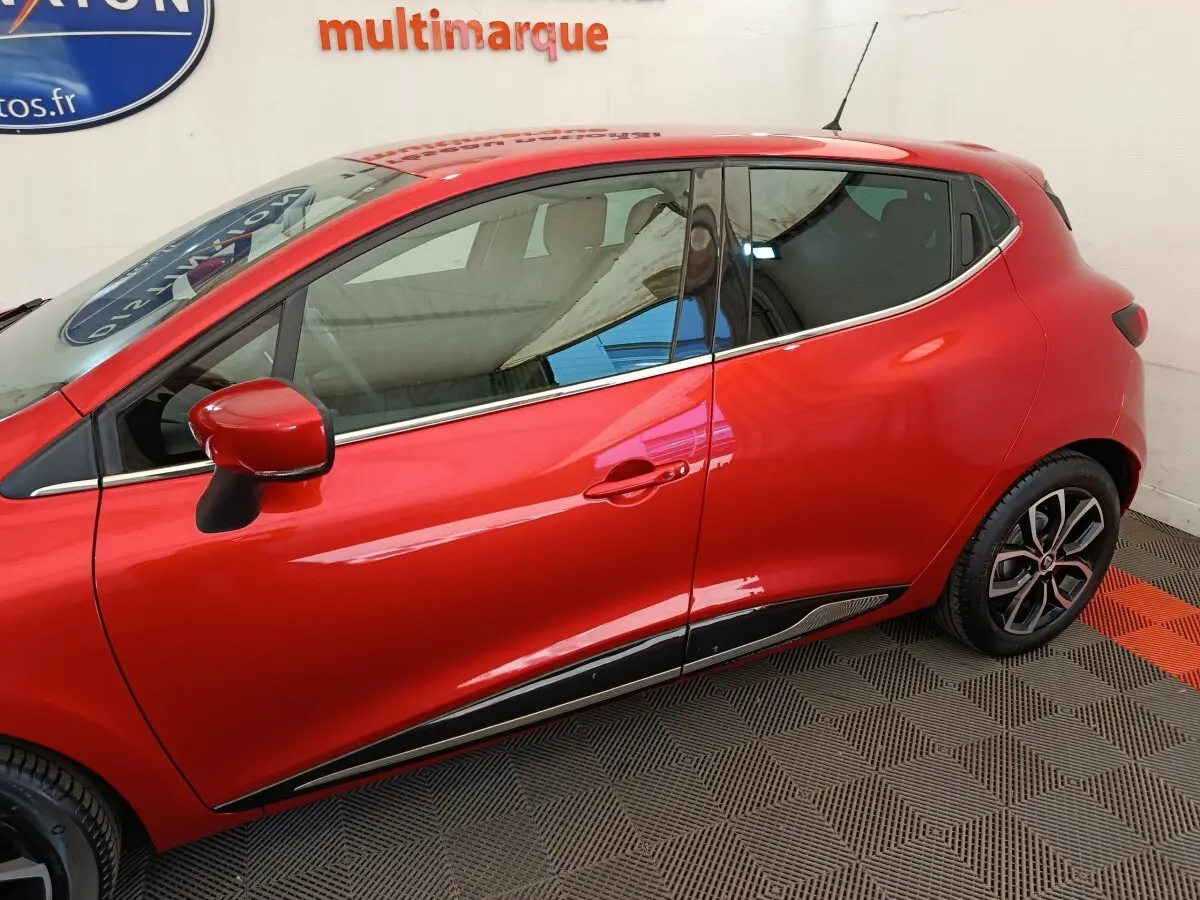 Profil côté gauche de la Renault Clio Intens rouge 2018, mettant en valeur les jantes et les détails chromés sur la porte.