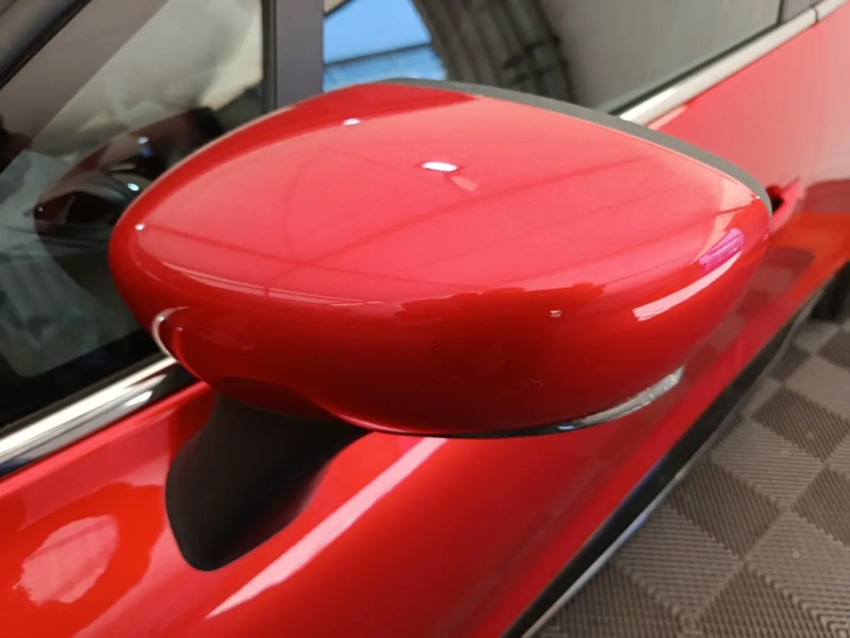 Rétroviseur droit rouge vif de Renault Clio Intens 2018, vue rapprochée sur la portière et la carrosserie brillante.