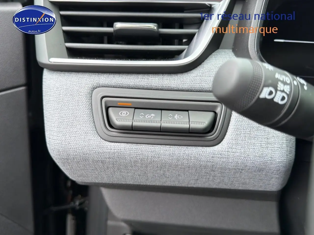 Détail des commandes d'éclairage et verrouillage sur tableau de bord tissu gris clair d'une Renault Clio V noire.