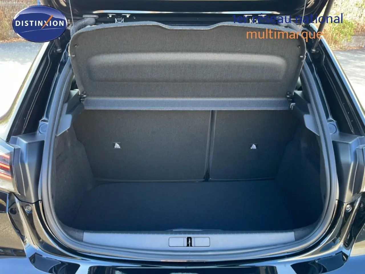 Coffre ouvert vu de l'arrière d'une Peugeot 208 Hybrid 110ch noir perla metal, espace de chargement vide et propre.