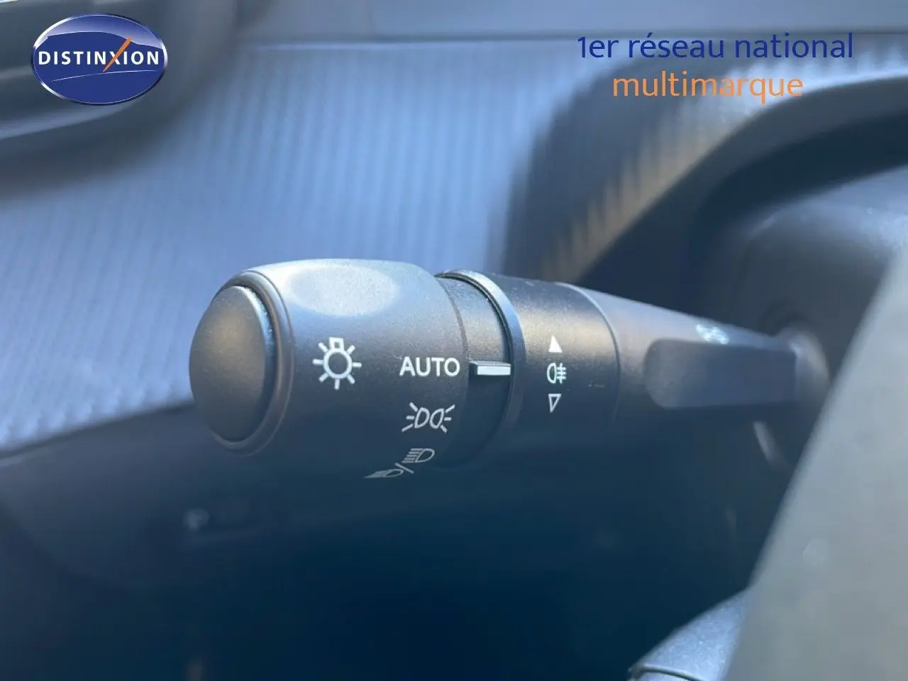 Gros plan sur la commande des phares du Peugeot 208 Hybrid 110ch, intérieur noir, détails des symboles lumineux visibles.