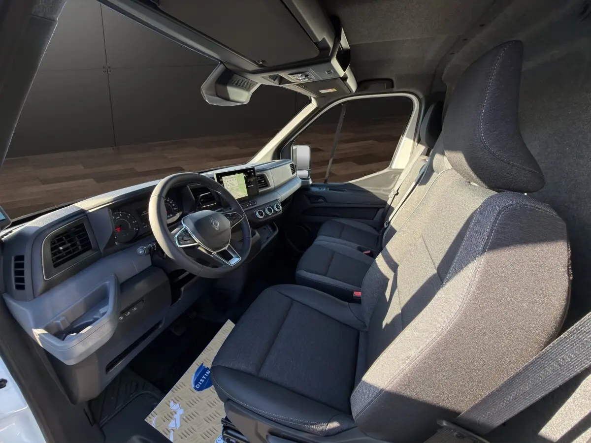 Vue intérieure côté conducteur du Renault Master blanc 2026, montrant le tableau de bord et les sièges avant gris.