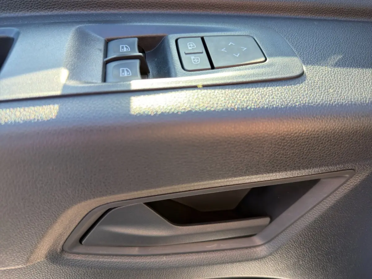 Gros plan sur la commande des vitres et réglage des rétroviseurs côté conducteur dans un Renault Master blanc.