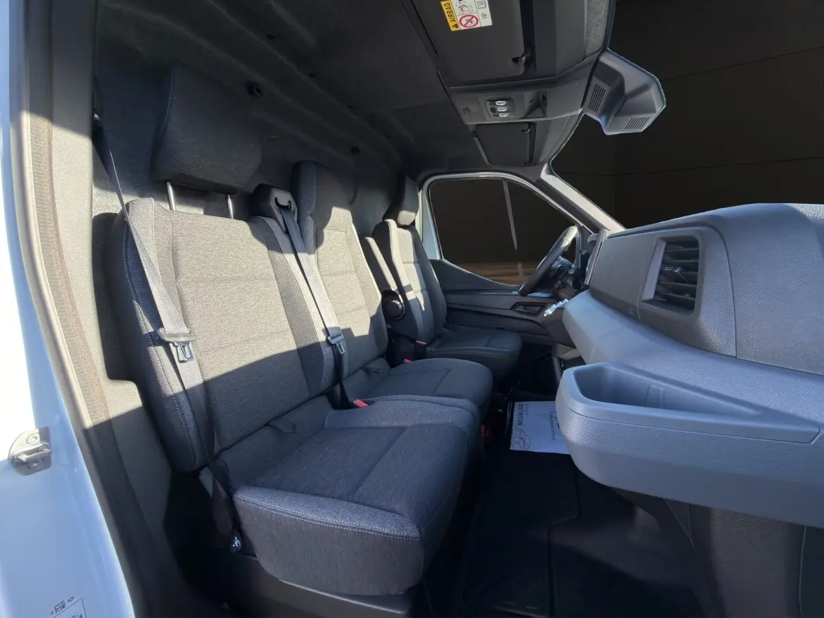 Vue intérieure côté passager du Renault Master blanc 2026, montrant les sièges gris et le tableau de bord moderne.