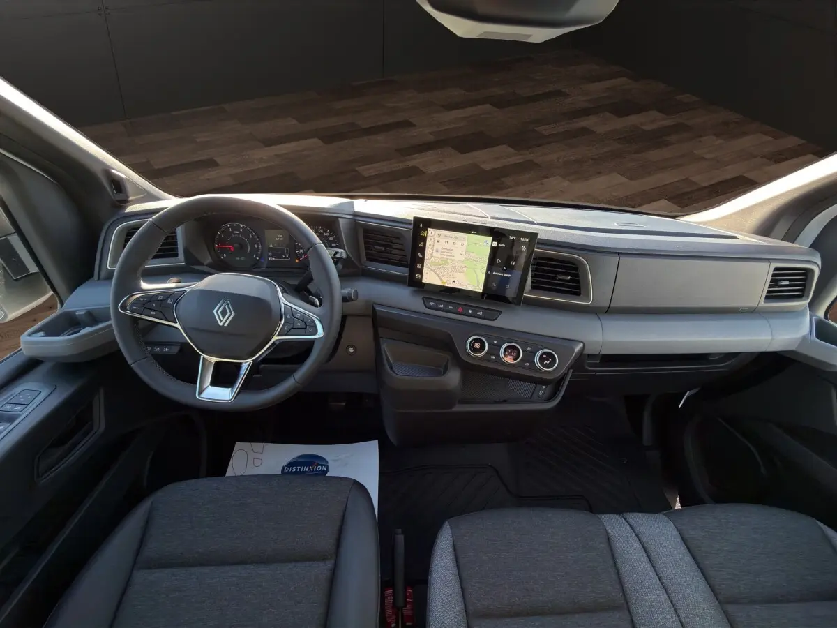 Vue intérieure avant du Renault Master 2026 avec tableau de bord gris, écran tactile central et volant multifonctions.