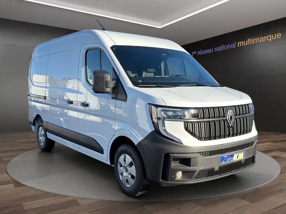 Renault Master blanc en vue 3/4 avant droit, avec calandre noire distinctive et feux LED allumés.