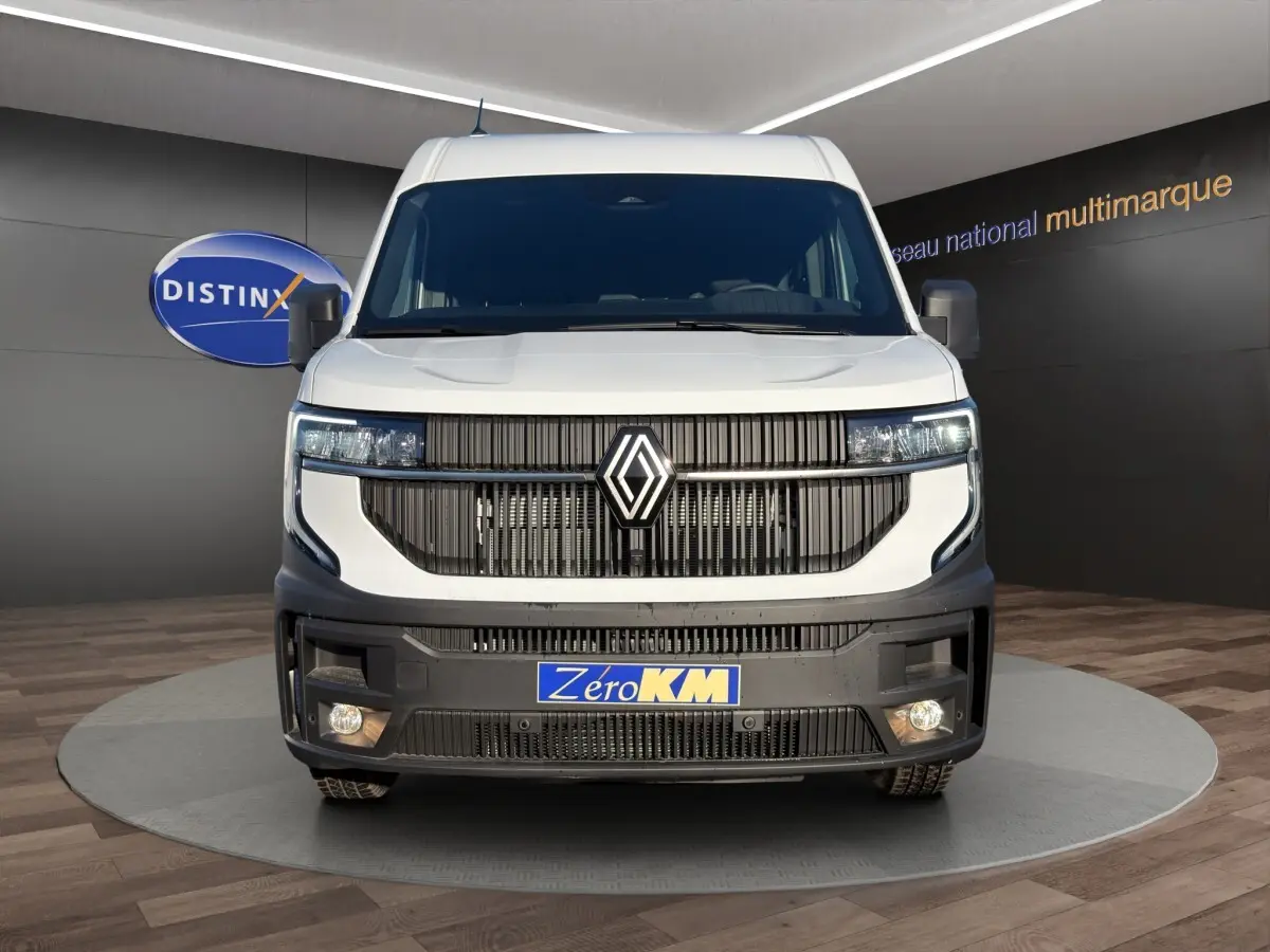 Vue frontale d’un Renault Master blanc avec calandre noire verticale et feux LED allumés en intérieur showroom.