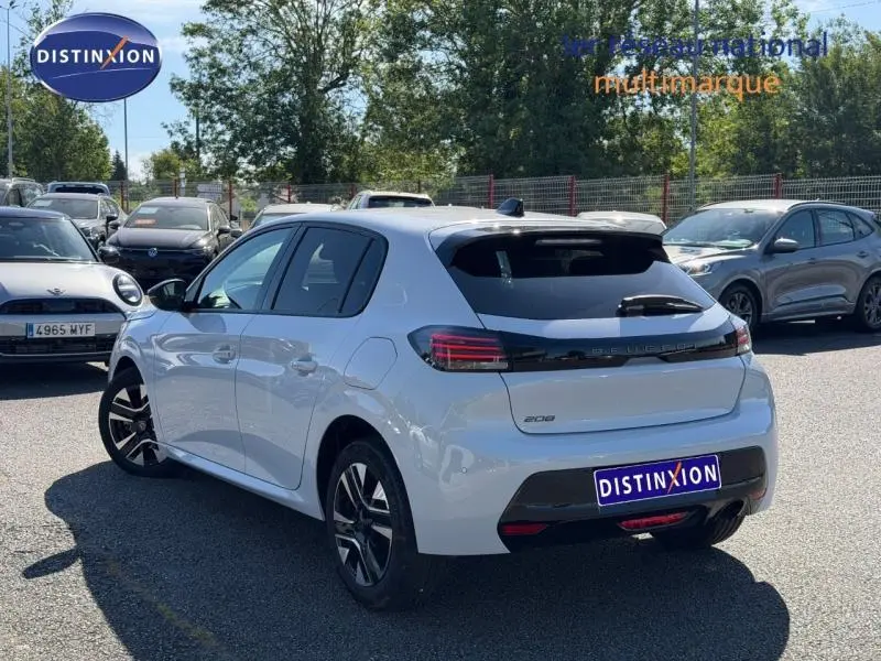 Peugeot 208 blanc Okénite vue 3/4 arrière droit, feux arrière LED et jantes alliage distinctives visibles.