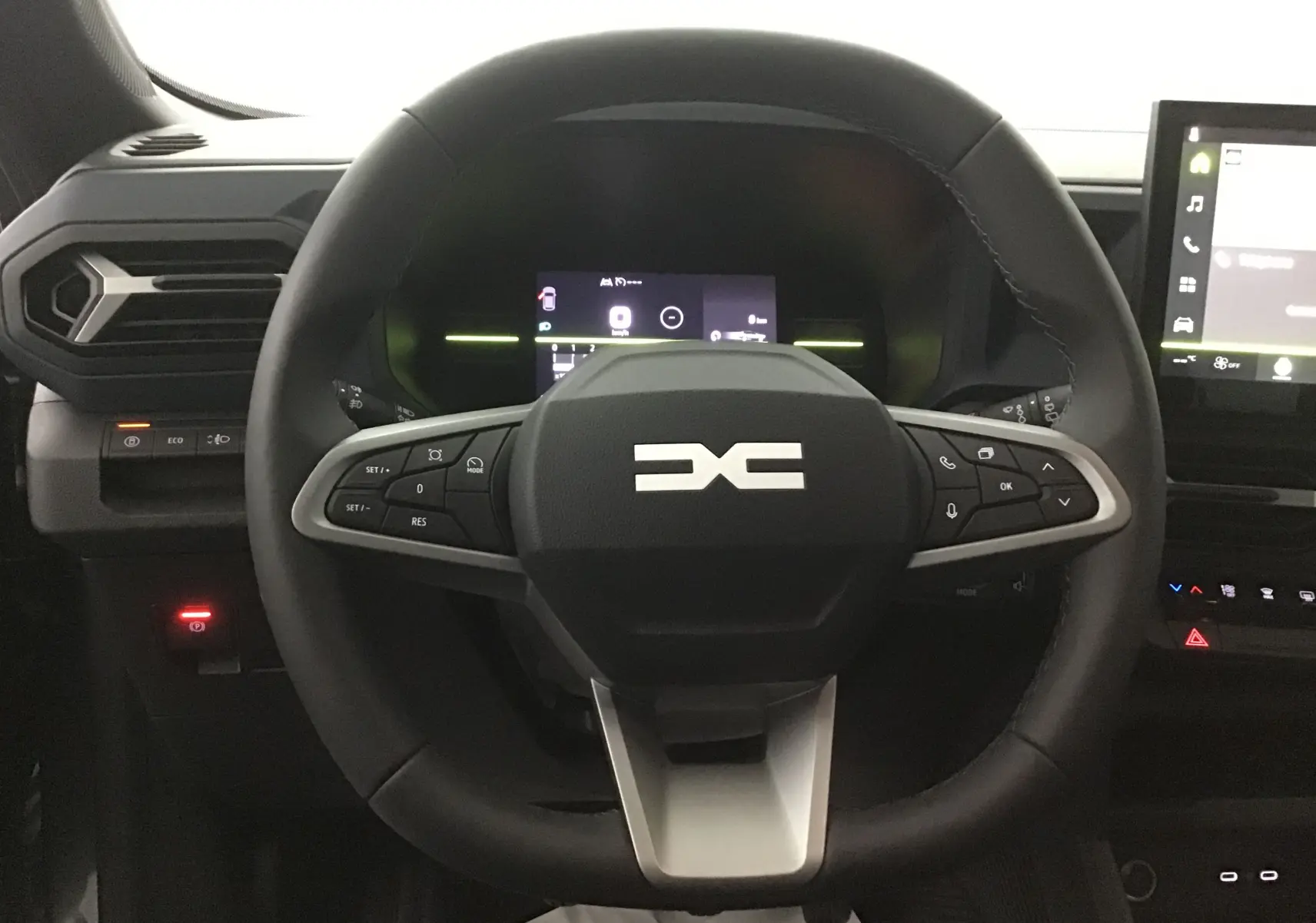 Vue rapprochée du volant noir du Dacia Bigster 2025 avec commandes intégrées et tableau de bord numérique éclairé.